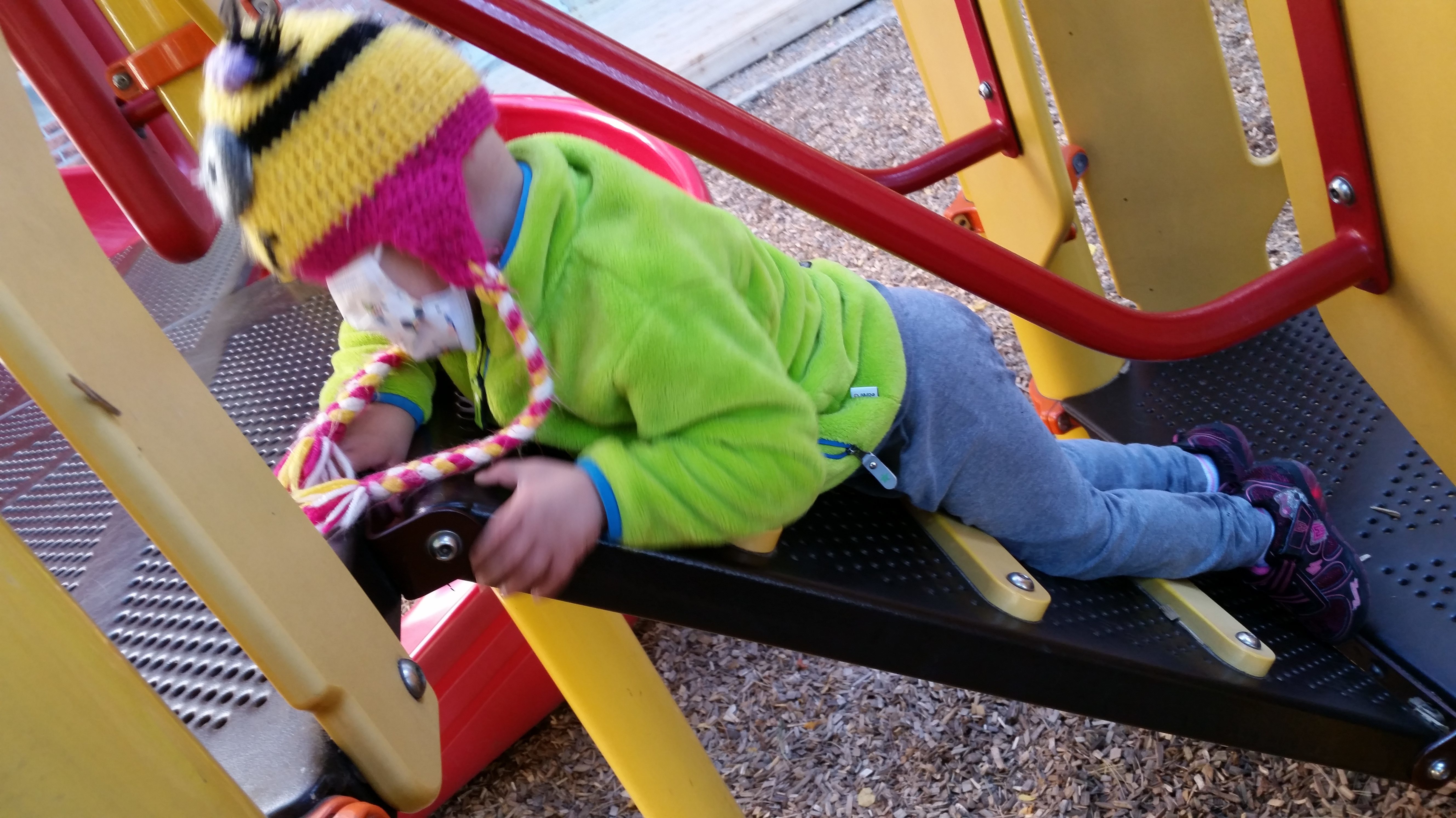 Sam climbing the ramp stairs on the playground equipment at the school across from RMH