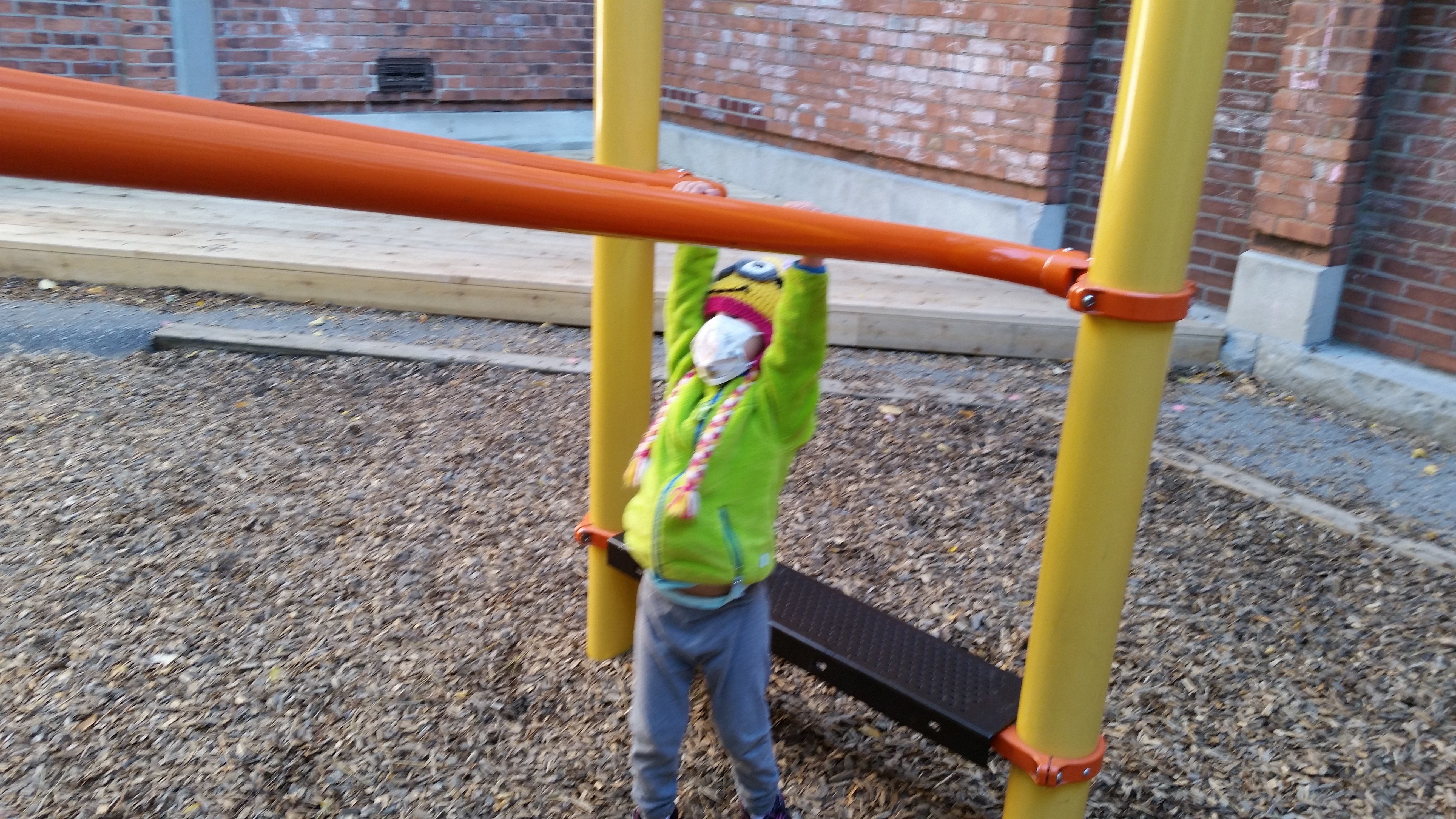 Sam on the monkey bars on the playground equipment at the school across from RMH