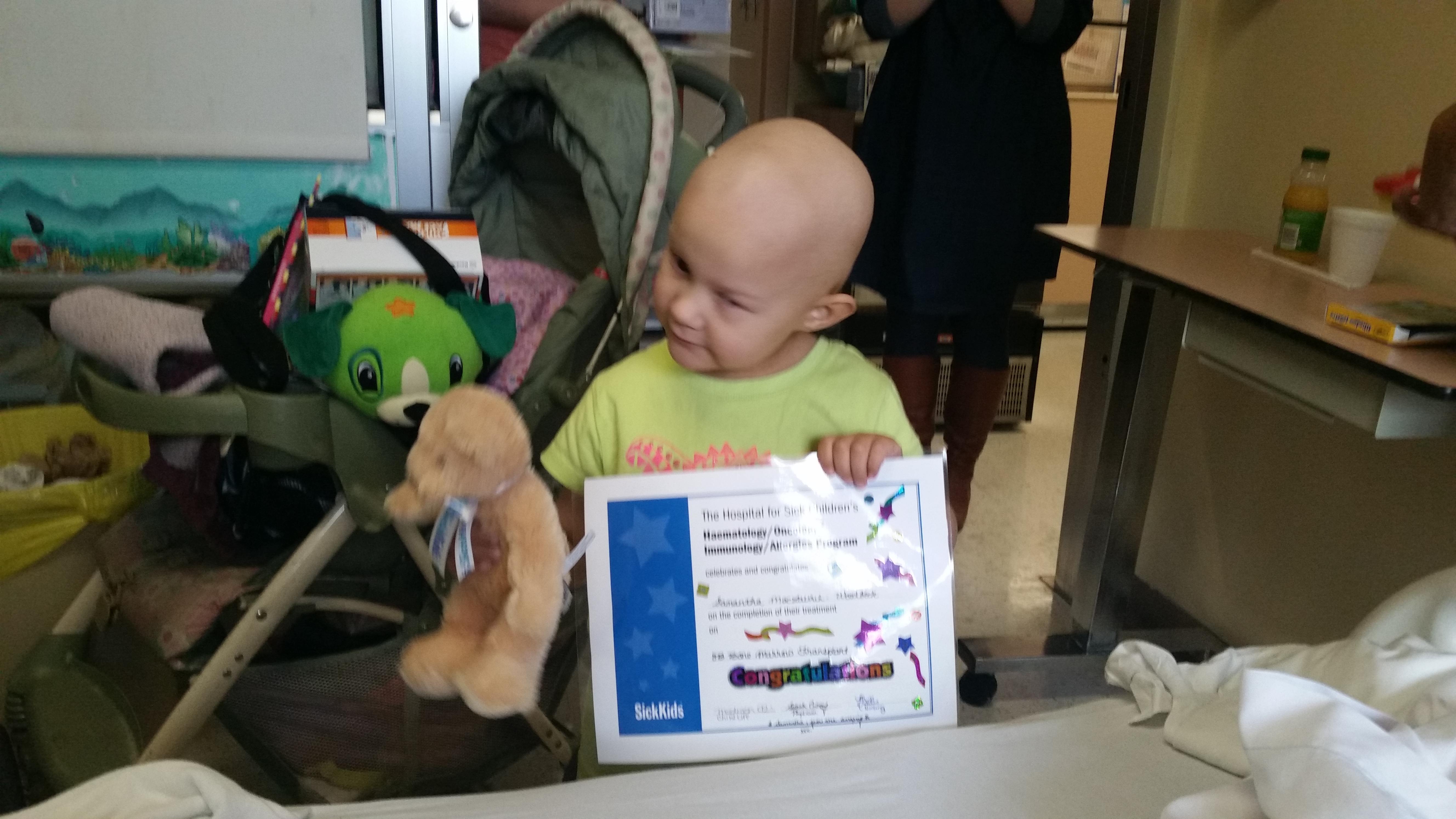 Sam with her certificate and bear on Discharge Day at SickKids